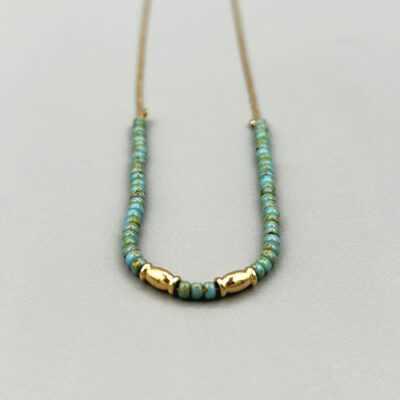 Détail collier doré a l'or 18 carats avec perles de verre japonaises turquoises et maille serpent. Packshot sur fond gris.