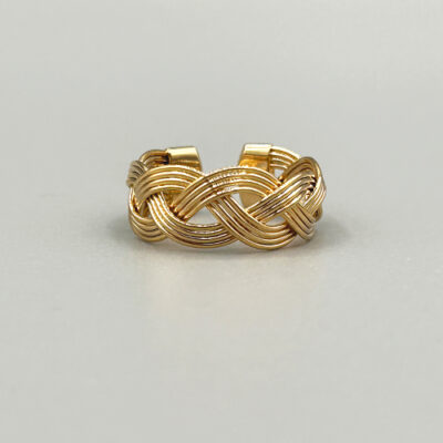 Bague assez large plaquée or 18 carats. Il s'agit d'une bague tressée de quatre fils d'or. Packshot sur fond gris. Prise de vue de face.